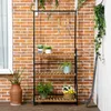 A plant stand with plants on a wooden deck against a brick wall. Produktbild-Vorschau