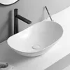 A white ceramic washbasin with a black faucet on a white countertop against a gray wall. Náhľad obrázku produktu