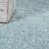 A close-up view of a light blue carpet with a small wooden block in the upper left corner. Produktbild-Vorschau
