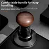 Close-up of a coffee tamper with a wooden handle on a dark surface. Náhled obrázku produktu