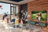 A family is enjoying time together in their living room, with a Samsung TV displaying a heartwarming image of a child and a dog. Produktbild-Vorschau