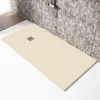 A beige shower tray with a square drain in the center, set against a stone-tiled wall and wooden decking. Produktbild-Vorschau