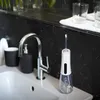 A close-up shot of a water flosser and a faucet on a bathroom sink. Produktbild-Vorschau