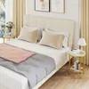 A bedroom scene featuring a bed with pillows and blankets, and two small side tables. The side table on the right has a lamp and books. Náhľad obrázku produktu