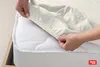 Hands are shown putting a fitted sheet onto a mattress. Produktbild-Vorschau