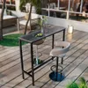 A bar table and stools set on a wooden deck with palm trees and lounge furniture in the background. Podgląd zdjęcia produktu