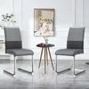 Two gray dining chairs are shown in a well-lit room with a small side table and a painting on the wall.