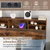 A close-up view of a bed frame's headboard with integrated storage and charging features, showing decorative items and a tablet charging. Náhled obrázku produktu