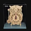 A wooden owl-shaped mechanical clock displayed inside a clear acrylic case. Produktbild-Vorschau