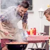 A father and son are grilling sausages outdoors. Produktbild-Vorschau