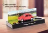 A model of a red Volkswagen Beetle is displayed on a diorama with a scenic background of mountains and a lake. The model is on a black base with text and a red button. Produktbild-Vorschau