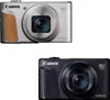 Two Canon PowerShot SX740 HS digital cameras, one silver and one black, are shown against a white background. Podgląd zdjęcia produktu
