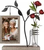 A decorative picture frame with a metal tree branch holding a photo and a glass vase with flowers. Produktbild-Vorschau