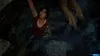 A woman is hanging from a ledge in a dark, rocky environment, reaching upwards. Náhled obrázku produktu