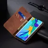 A Huawei P30 Pro phone in a brown leather wallet case, with cards and money inserted, placed on a dark surface next to a smartwatch. Produktbild-Vorschau