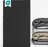A black fitted sheet is shown folded on the left, with a stack of fitted sheets in various colors on the right. Produktbild-Vorschau