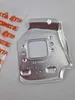 A metal part with a square cutout, likely a component for a machine, is placed on a light gray background. A clear plastic bag with orange branding is partially visible on the left. Produktbild-Vorschau
