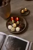 A collection of LED tea lights arranged on a tray with pinecones, next to a book and a planter. Produktbild-Vorschau