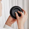 A person's hands are adjusting a black dial on a black circular object, possibly a lid or a component of a larger product. Náhľad obrázku produktu