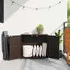 An outdoor storage cabinet on a balcony, filled with cushions and a basket, with a folded chair next to it. Podgląd zdjęcia produktu