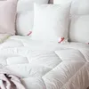 A close-up view of white bedding, including pillows and a comforter. Produktbild-Vorschau