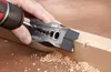 A person is using a drill with a jig to drill a hole in a piece of wood, with sawdust scattered around. Anteprima dell’immagine prodotto