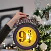 A hand is holding a Harry Potter themed "Platform 9 3/4" light decoration, which is being hung on a Christmas tree. Produktbild-Vorschau