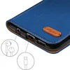 A close-up view of the bottom edge of a blue flip phone case, showing ports and a leather tag. Produktbild-Vorschau