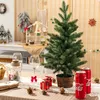 A small artificial Christmas tree is set up on a table with festive decorations, including gift boxes, pinecones, and Coca-Cola cans. Náhľad obrázku produktu