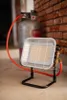 A portable gas heater connected to a gas cylinder, placed on a concrete floor next to a brick wall. Anteprima dell’immagine prodotto