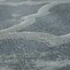 A close-up, angled view of a textured rug with a wavy pattern. Produktbild-Vorschau