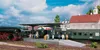 A model train station scene with a steam locomotive and passenger cars. Anteprima dell’immagine prodotto