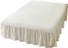 A white bed skirt with ruffles is shown on a bed. Produktbild-Vorschau
