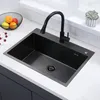A black kitchen sink with a black faucet is shown on a white countertop. Náhled obrázku produktu