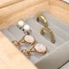 A close-up view of jewelry items stored in a wooden jewelry box with gray velvet lining. Voir les images du produit