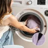 A woman is putting a light purple corduroy beanbag into a washing machine. Anteprima dell’immagine prodotto