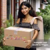 A woman is holding a package and has a bag over her shoulder, standing outside a building. Produktbild-Vorschau