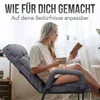 A woman is sitting in a recliner chair, reading a book and holding a mug. Produktbild-Vorschau