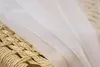 A close-up of white sheer fabric draped over a woven material. Produktbild-Vorschau