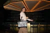 A woman stands in a bar, holding a tote bag. Produktbild-Vorschau