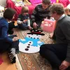 A family is sitting on the floor around a felt snowman craft kit. Náhľad obrázku produktu