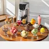 An ice cream maker is shown on a wooden table surrounded by various ice cream desserts and a milkshake. Podgląd zdjęcia produktu