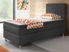 A single bed with a dark gray upholstered base and headboard, a white mattress, and a decorative pillow and throw with an orange and white chevron pattern. A framed picture of a bird hangs on the wall behind the bed. Produktbild-Vorschau