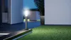 A modern outdoor lighting fixture illuminates a pathway and lawn at dusk. Produktbild-Vorschau