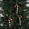 Three red and white striped candy cane ornaments hang on a Christmas tree. Produktbild-Vorschau