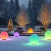 A snowy garden scene at dusk, decorated with colorful, glowing spherical solar lights and a small, illuminated Christmas tree. Produktbild-Vorschau