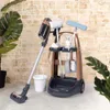 A toy cleaning cart with a vacuum cleaner and accessories, set against a brick wall. Produktbild-Vorschau
