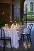 An outdoor table setting with string lights and candles. Náhled obrázku produktu