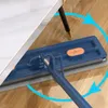 Blauer Flachwischer mit grauem Mikrofaserpad, positioniert unter einem weißen Tisch auf einem Holzboden, mit blauen kreisförmigen Pfeilen, die Bewegung anzeigen Produktbild-Vorschau