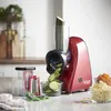 A red Russell Hobbs food processor with a cucumber being sliced into a glass bowl. Produktbild-Vorschau
